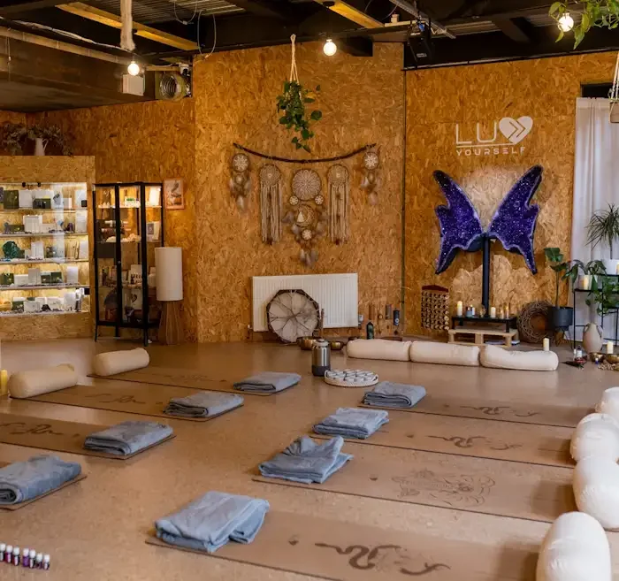 beautiful indoor yoga and meditation space with cork yoga mats, bolsters, and candles arranged in a circle, decorated with plants, dreamcatchers, and wall art.