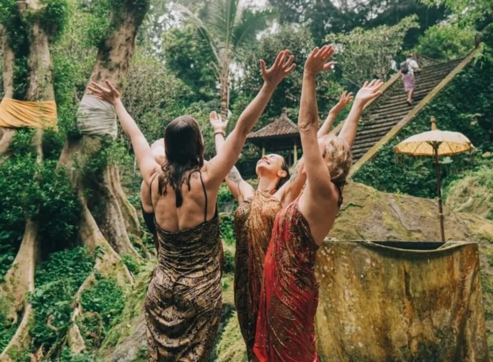 Four women standing with arms stretched to the sky in Bali, smiling and happy faces