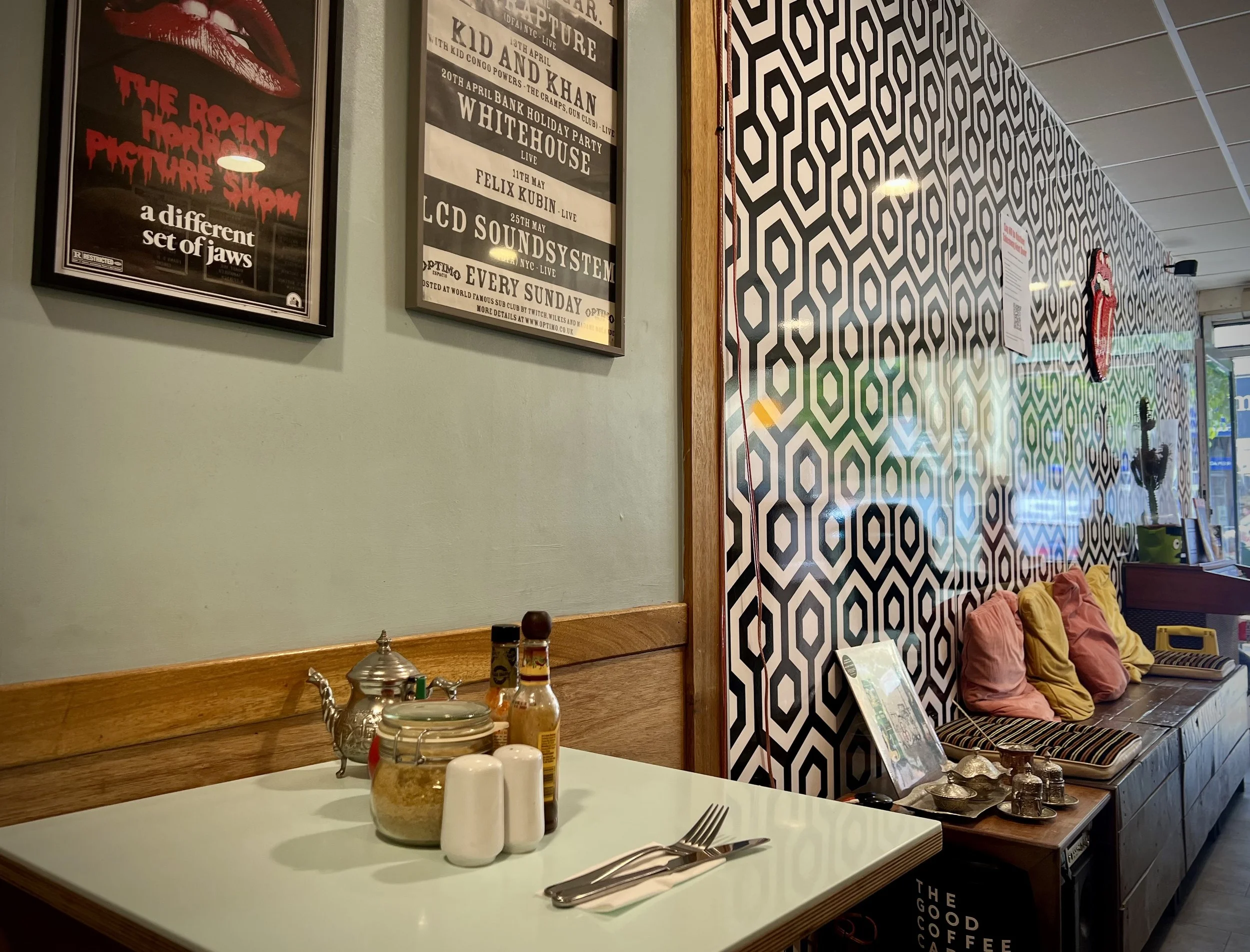 Close-up of a sandwich with sliced bread, shredded lettuce, sliced tomato, shredded carrots, sliced red cabbage, shredded chicken, and bacon on a light blue plate.
