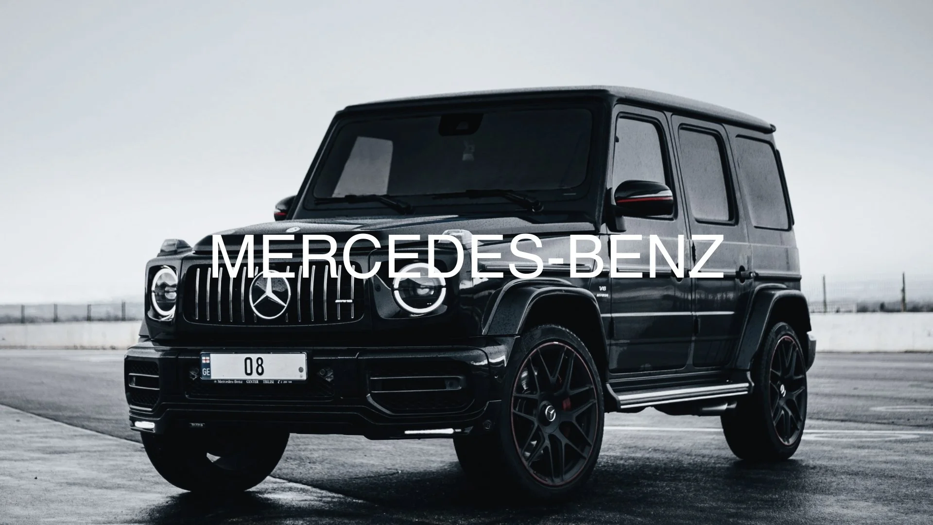 Black Mercedes-Benz G-Class SUV parked on an empty road in a cloudy setting with the Mercedes-Benz logo and name overlayed.