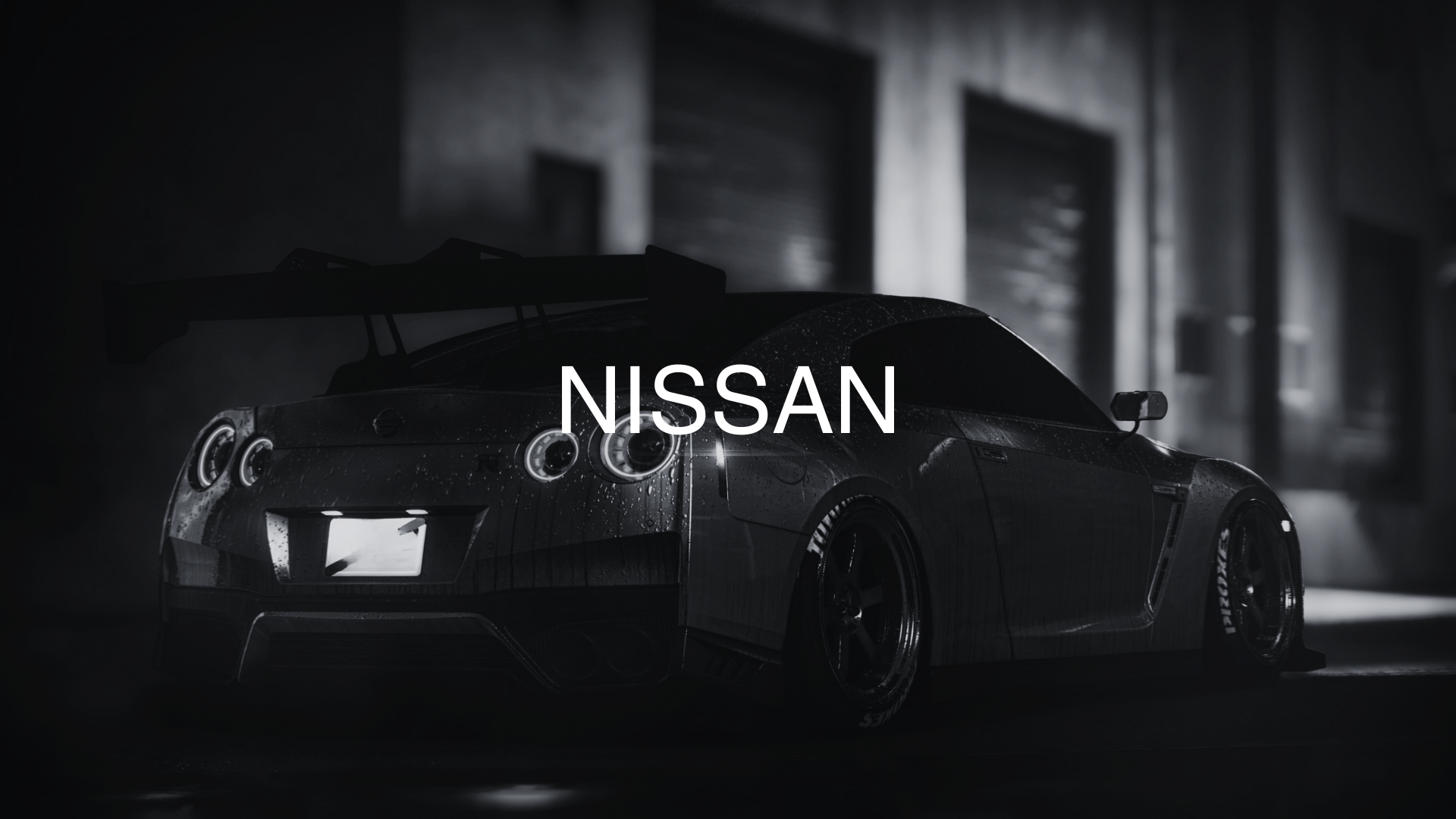 A dark, sleek Nissan sports car with a large rear wing, sitting in a dimly lit garage, wet and reflecting light on its surface.
