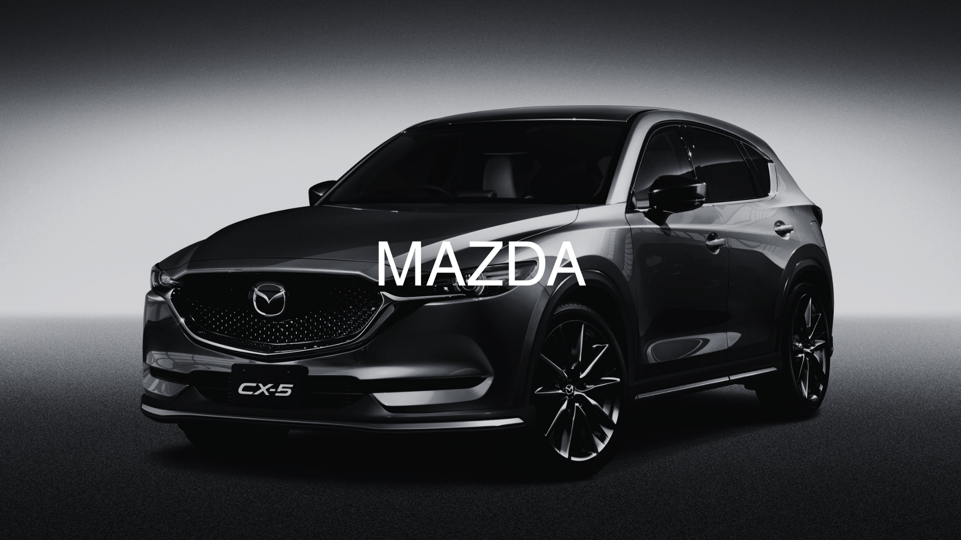 A black Mazda CX-5 SUV in a studio setting with a gray background and soft lighting.