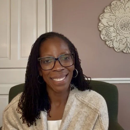 Leana Sykes, M.Ed, LPC, ACS, licensed counselor and founder of Mid-Atlantic Evaluations, smiling in front of a beige wall with decorative white wall art at her Haddonfield, NJ office