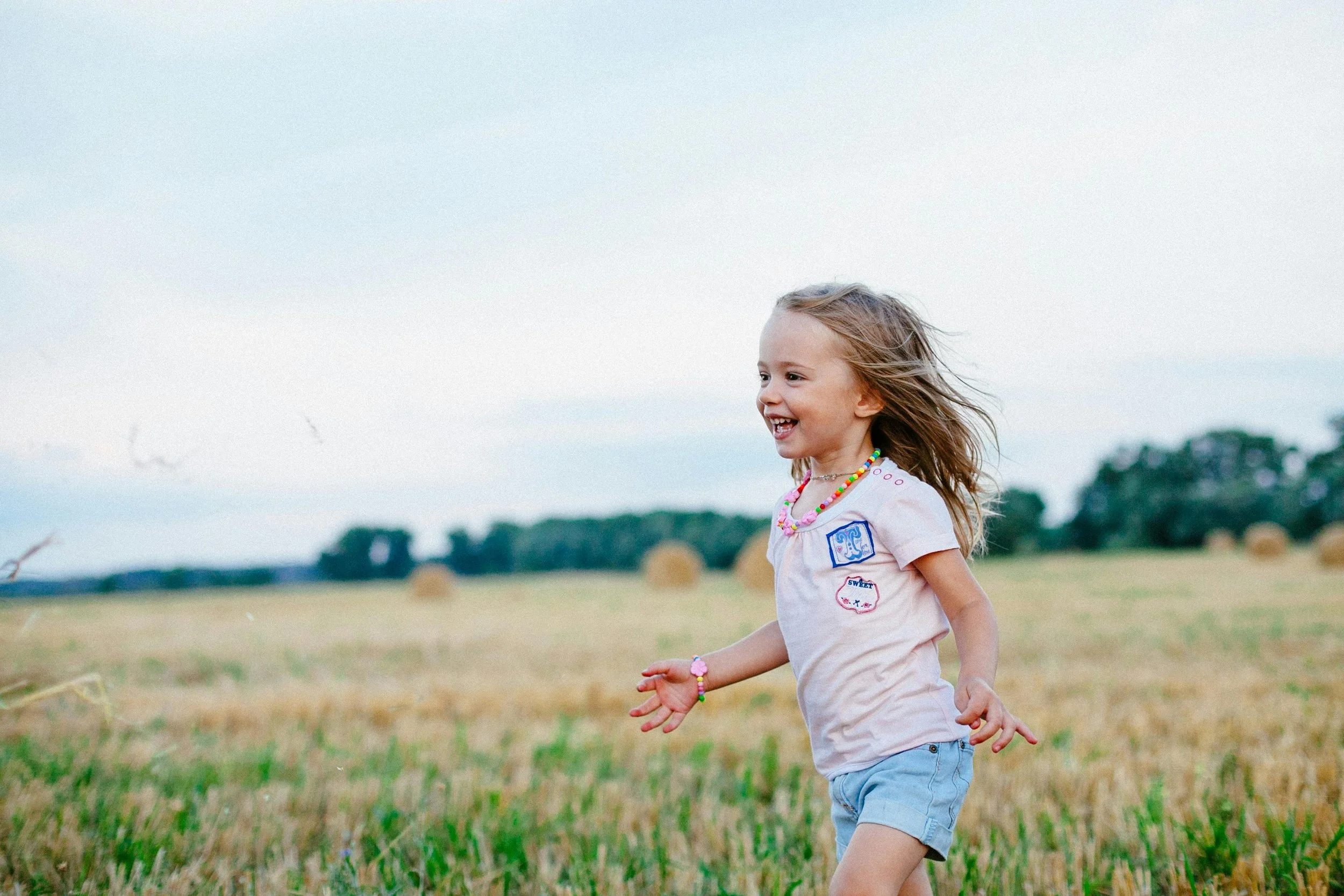 A child runs outside in the grass.
