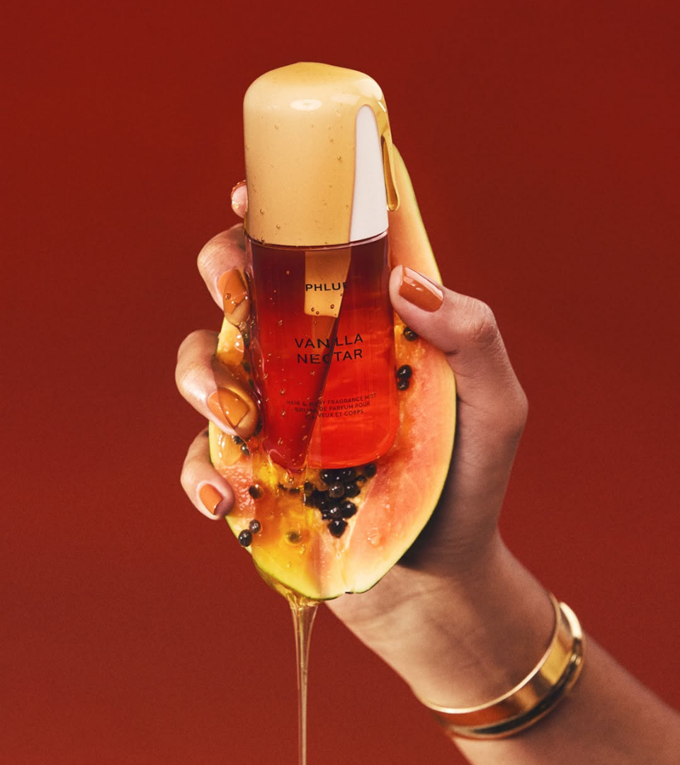 Vanilla Nectar by Phlur 2025 – papaya and vanilla hair and body mist, hand squeezing a papaya and holding a mist drenched in nectar, sensual packshot, Papaya Undressed trend Dark Tropicana by WSSC