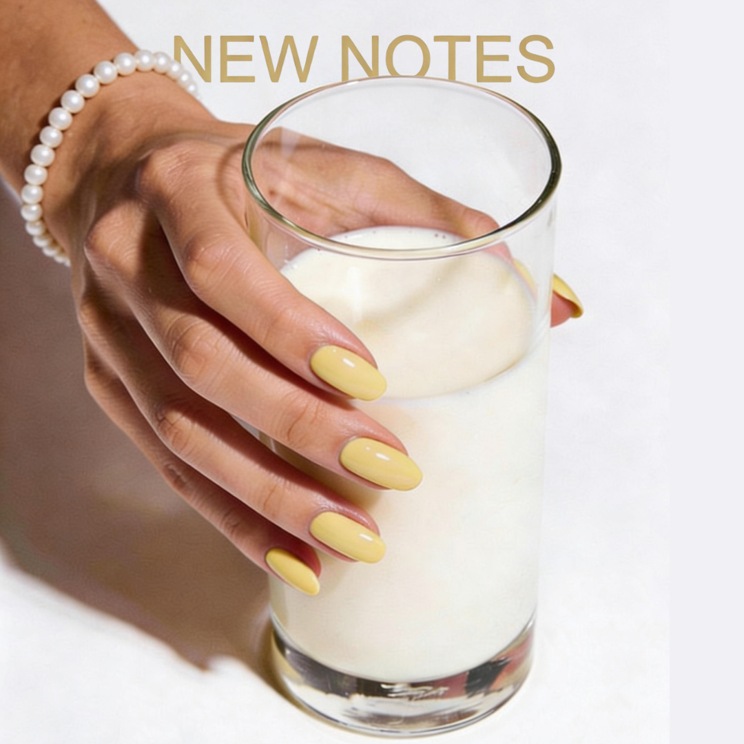 Hand with yellow manicure and pearls bracelet holding a glass of milk against New Notes branded background, editorial visual for Latte Banana New Notes ScentLab concept by WSSC