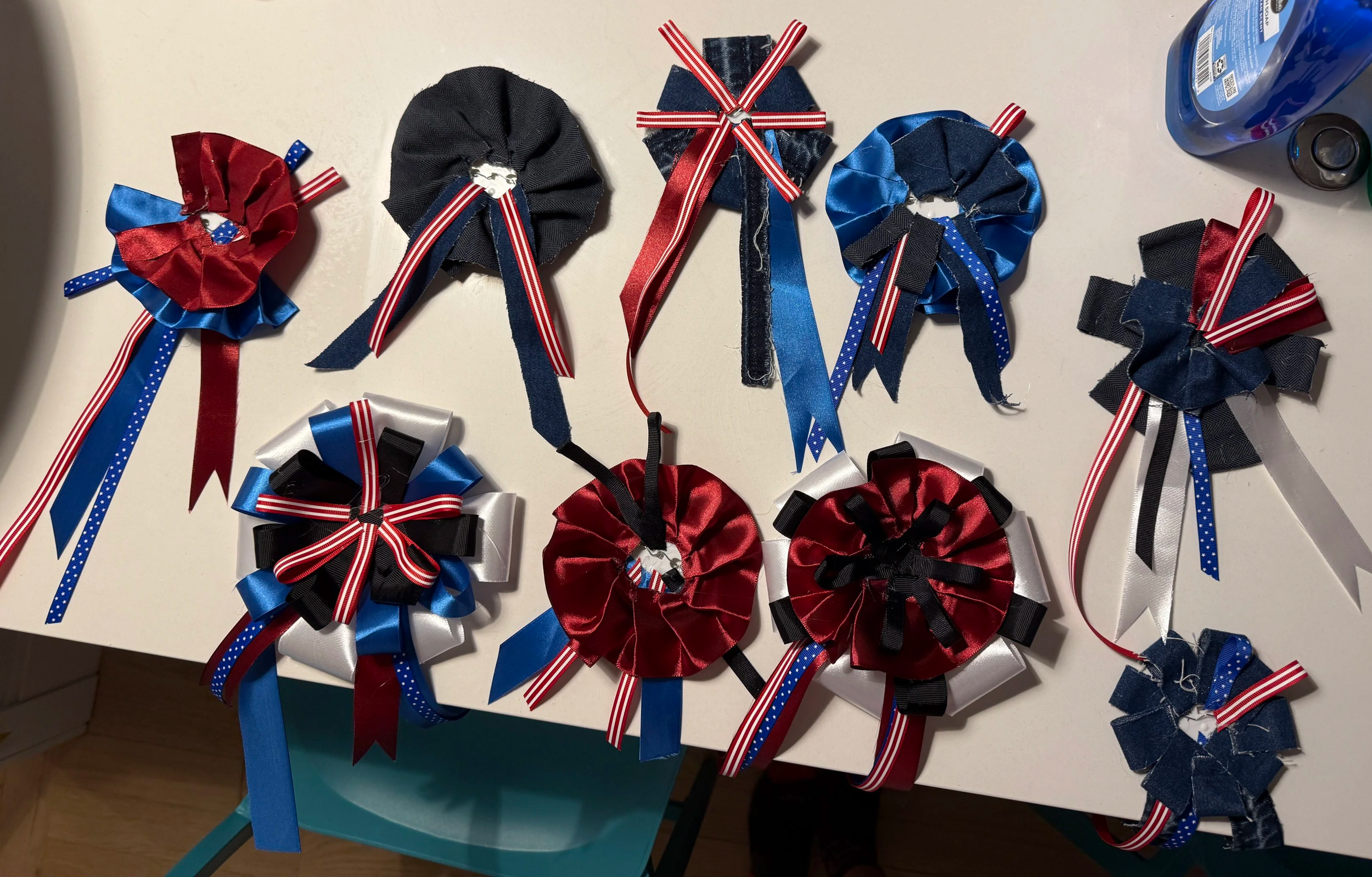 The bases of the assassins' buttons were intended to represent each of them visually; Booth and Guiteau's are more ornate, Moore's is purposefully messy and asymmetrical, and Czolgosz's is primarily denim to represent his working class background 