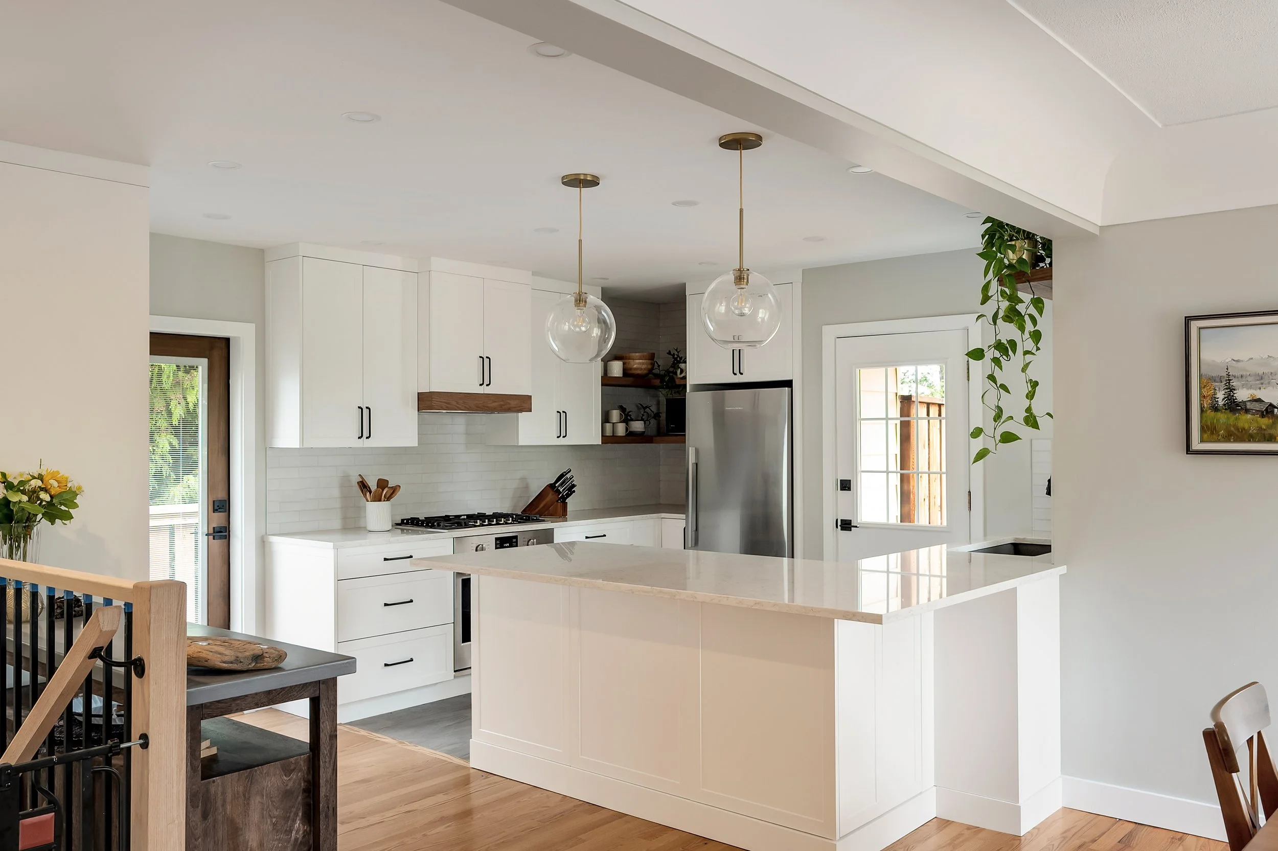 white kitchen with wood accents and glass light fixtures