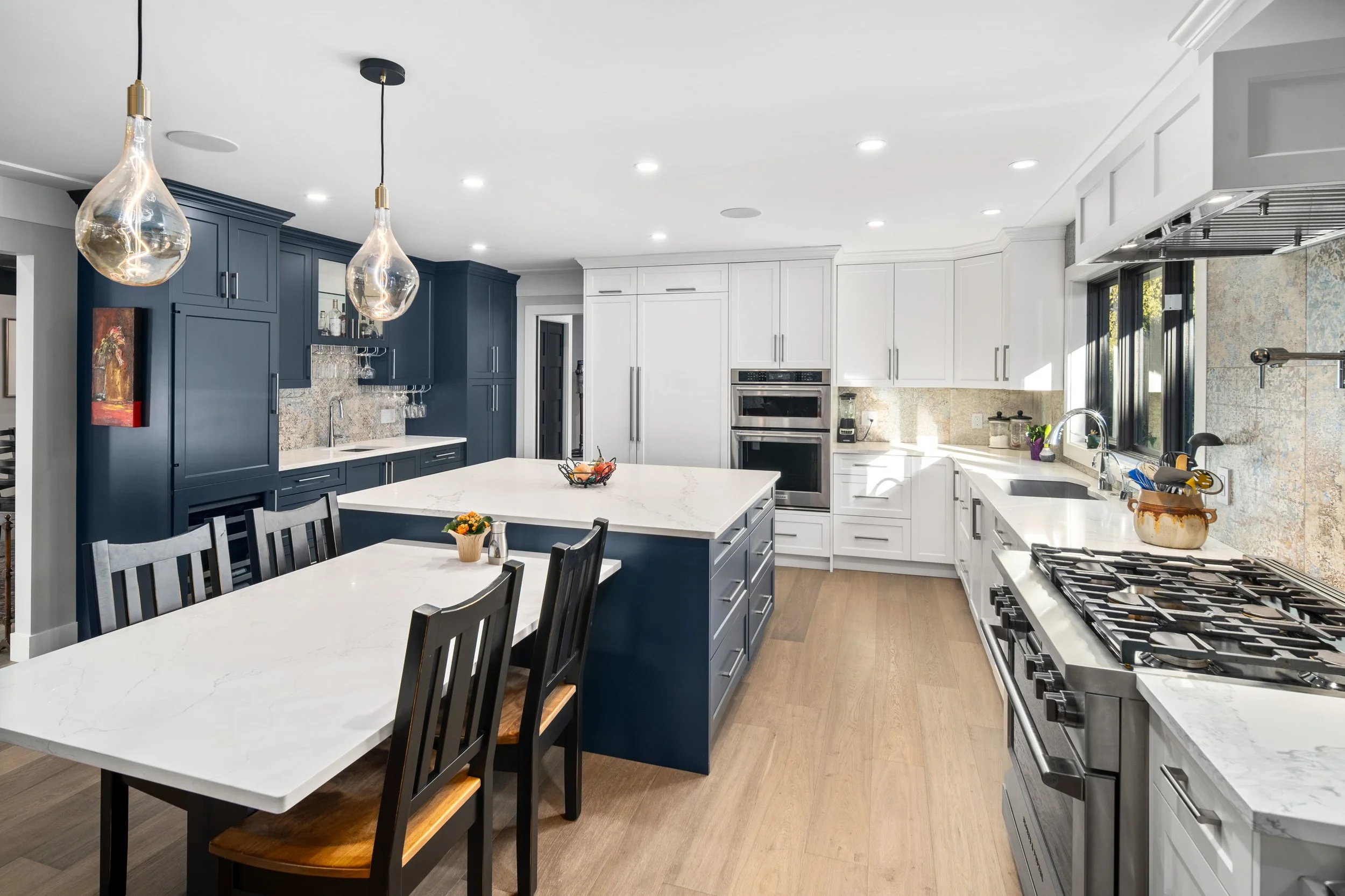 Modern bathroom with a black and white color scheme, featuring a freestanding bathtub, marble wall, black cabinetry, white countertop, and patterned tile floor.