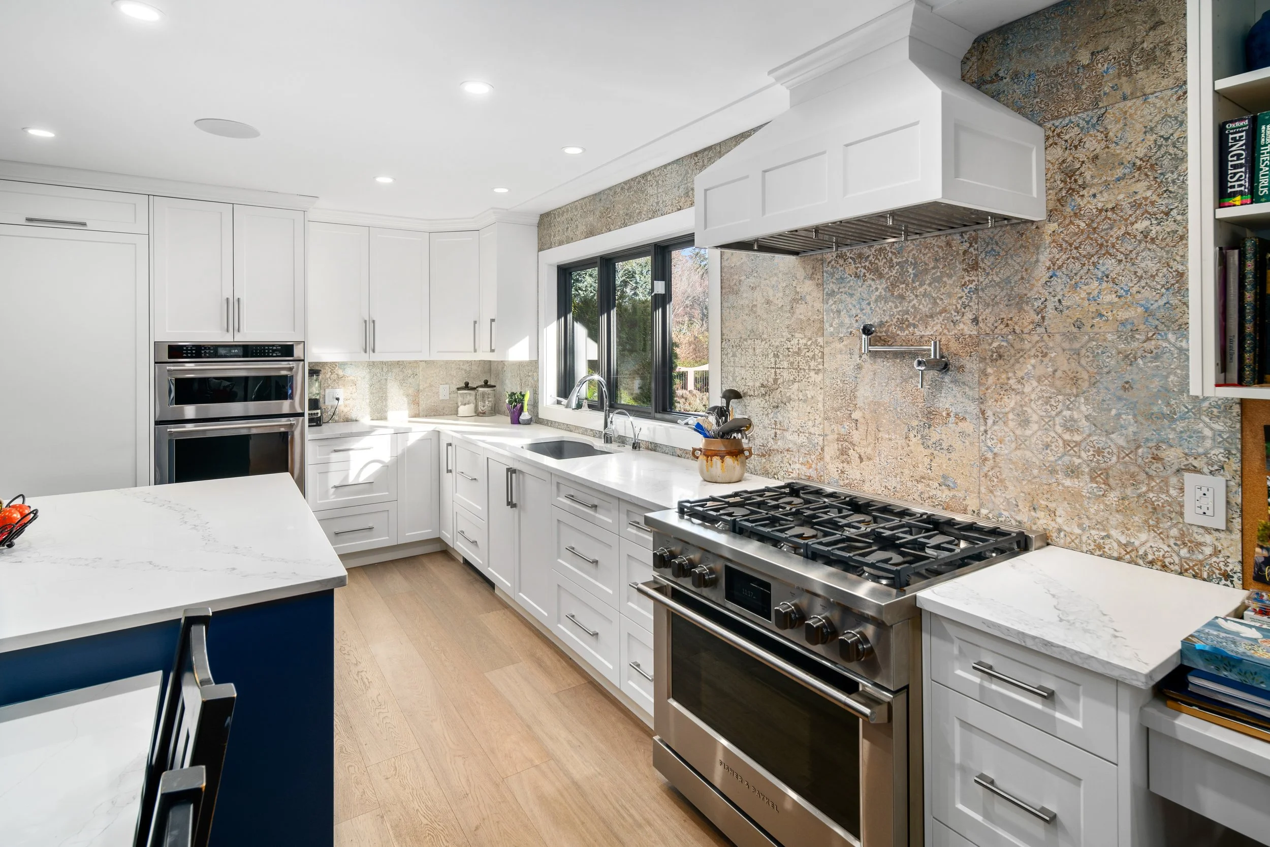 Modern bathroom featuring a black and white freestanding bathtub, a marble tiled walk-in shower, a large ornate mirror, and blue towels hanging on the wall.