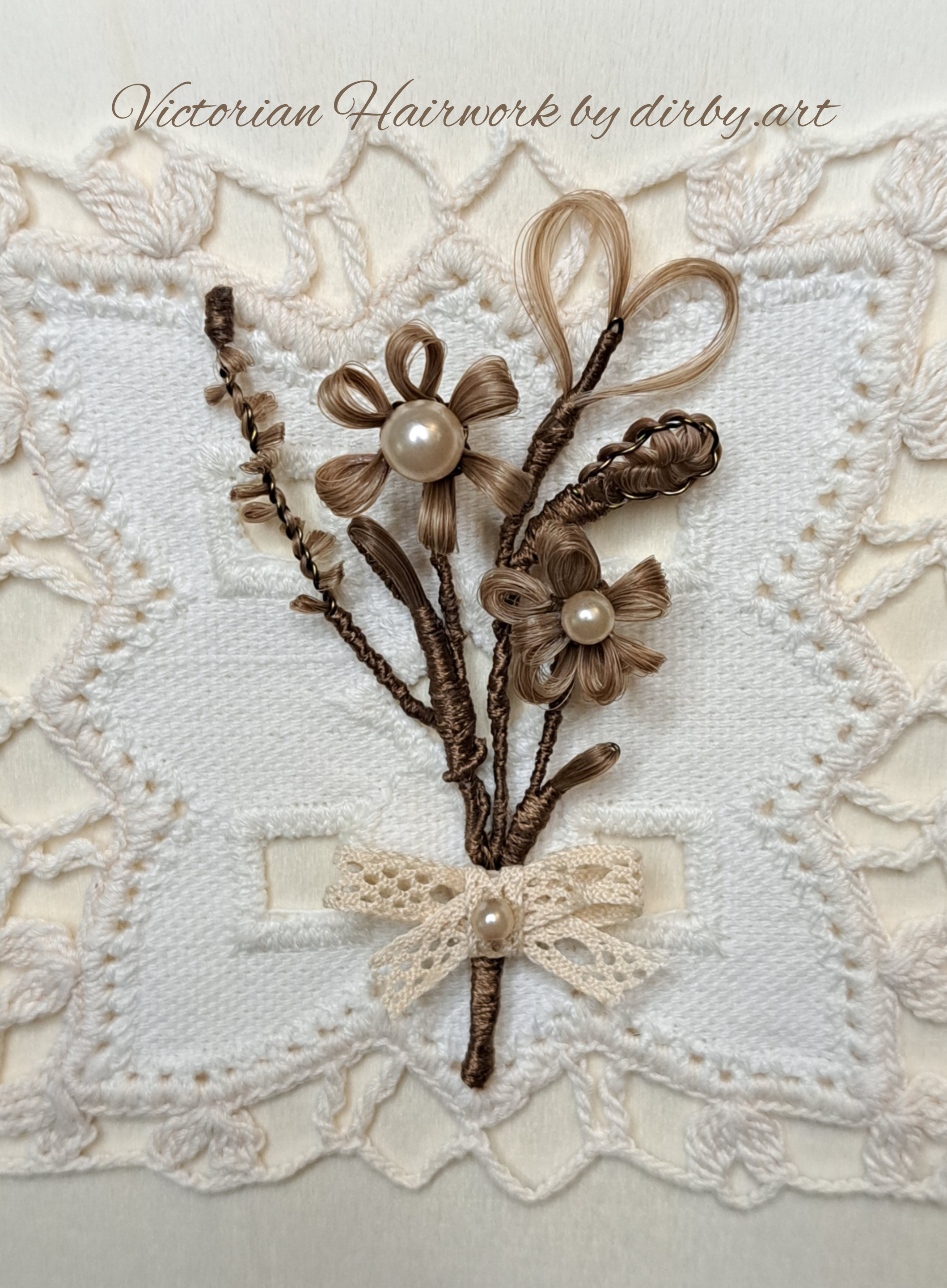 A Victorian-style hairwork posy bouquet, made of brown human hair, placed on a white crochet doily, created by historian and artist Diane Irby.