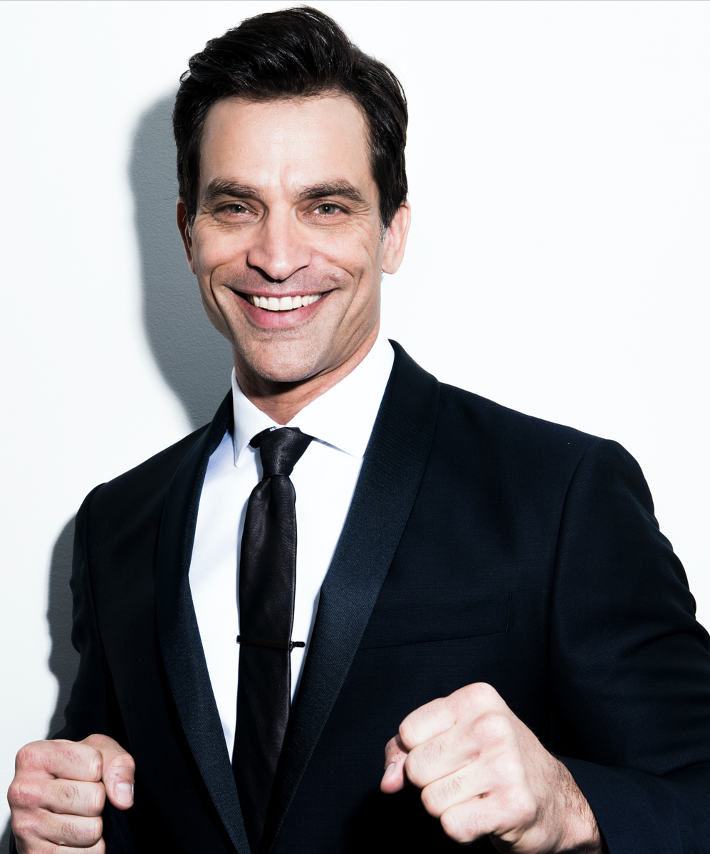 Man in a suit smiling and holding fists up.
