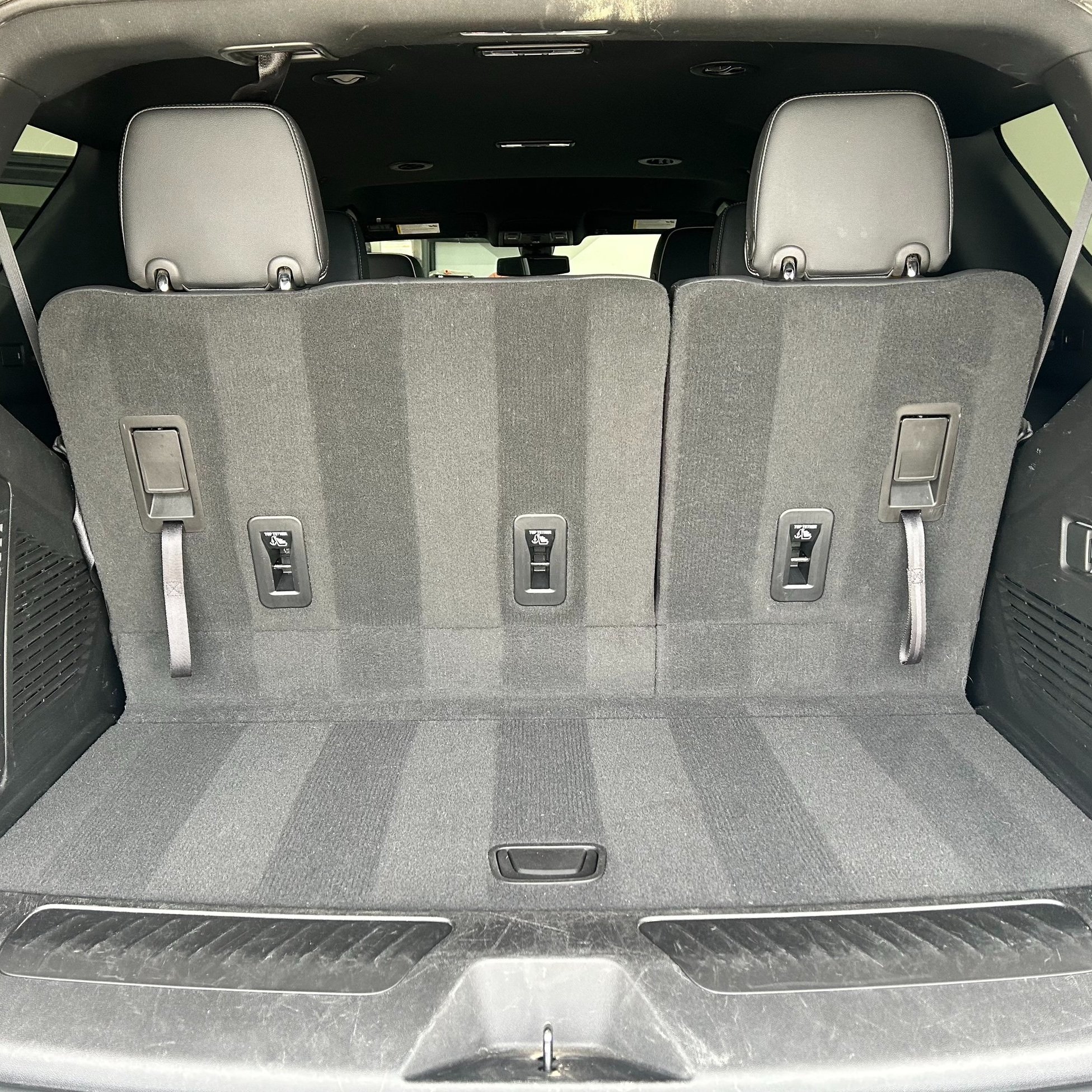 Back of an SUV with folded-down third-row seats, showing the interior cargo space.