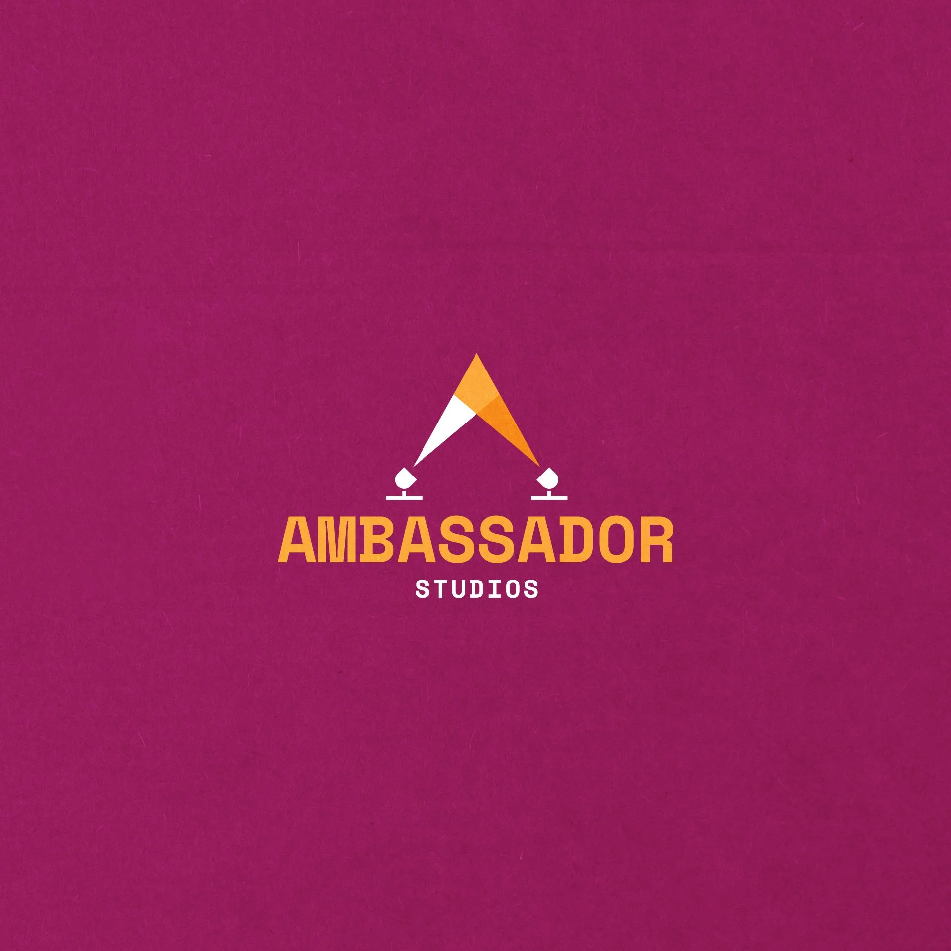 Logo for Ambassador Studios featuring a stylized person with a megaphone pointing upward, with the text 'AMBASSADOR STUDIOS' beneath it on a pink background.