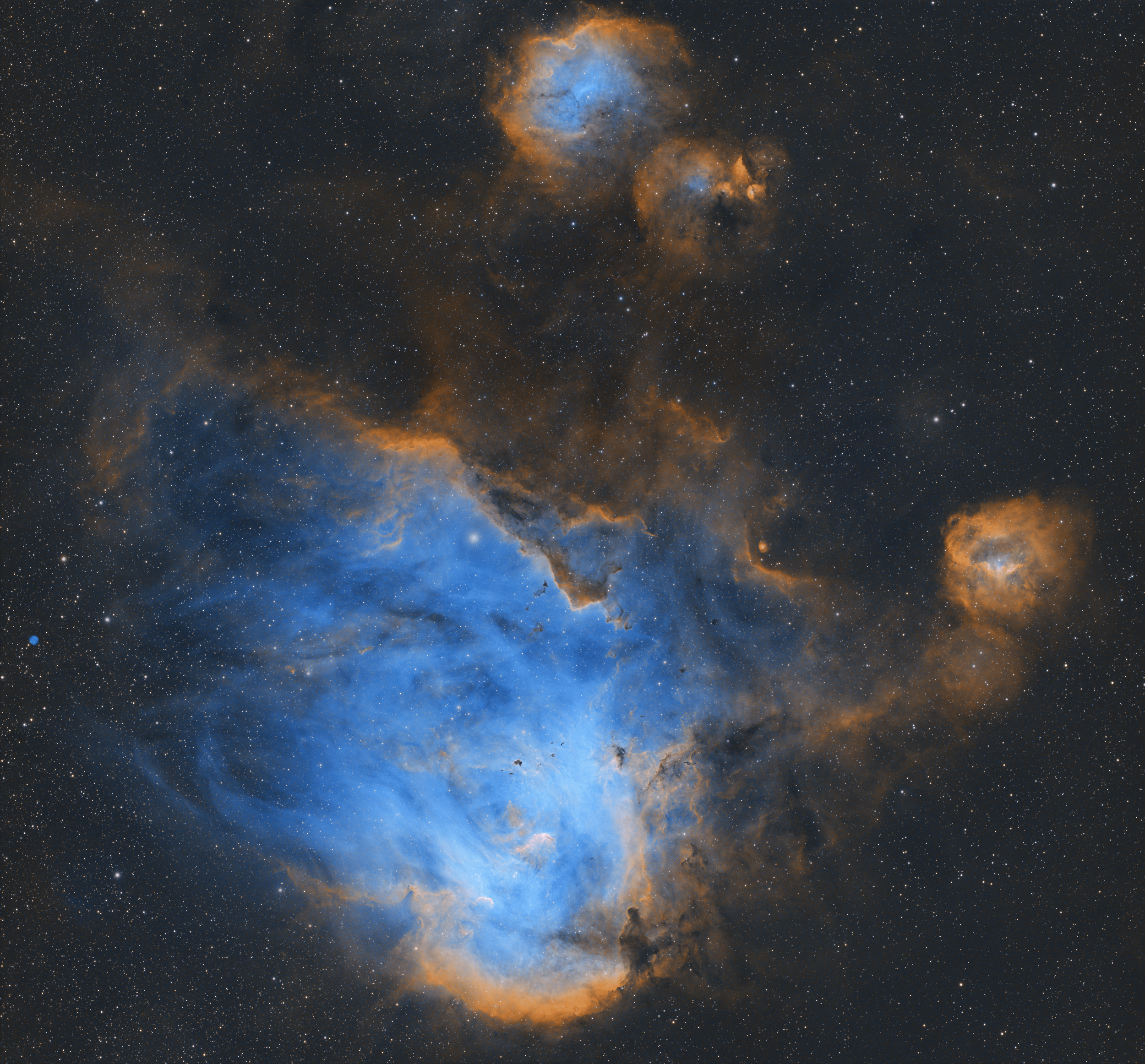 A detailed view of a colorful nebula in space with blue, orange, and black regions, surrounded by numerous white stars.