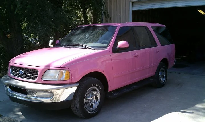 A bright pink Ford Expedition SUV parked in front of a garage, photographed in August 2010 — Jackie Hynes's personal vehicle she drove from 2010 to 2015.