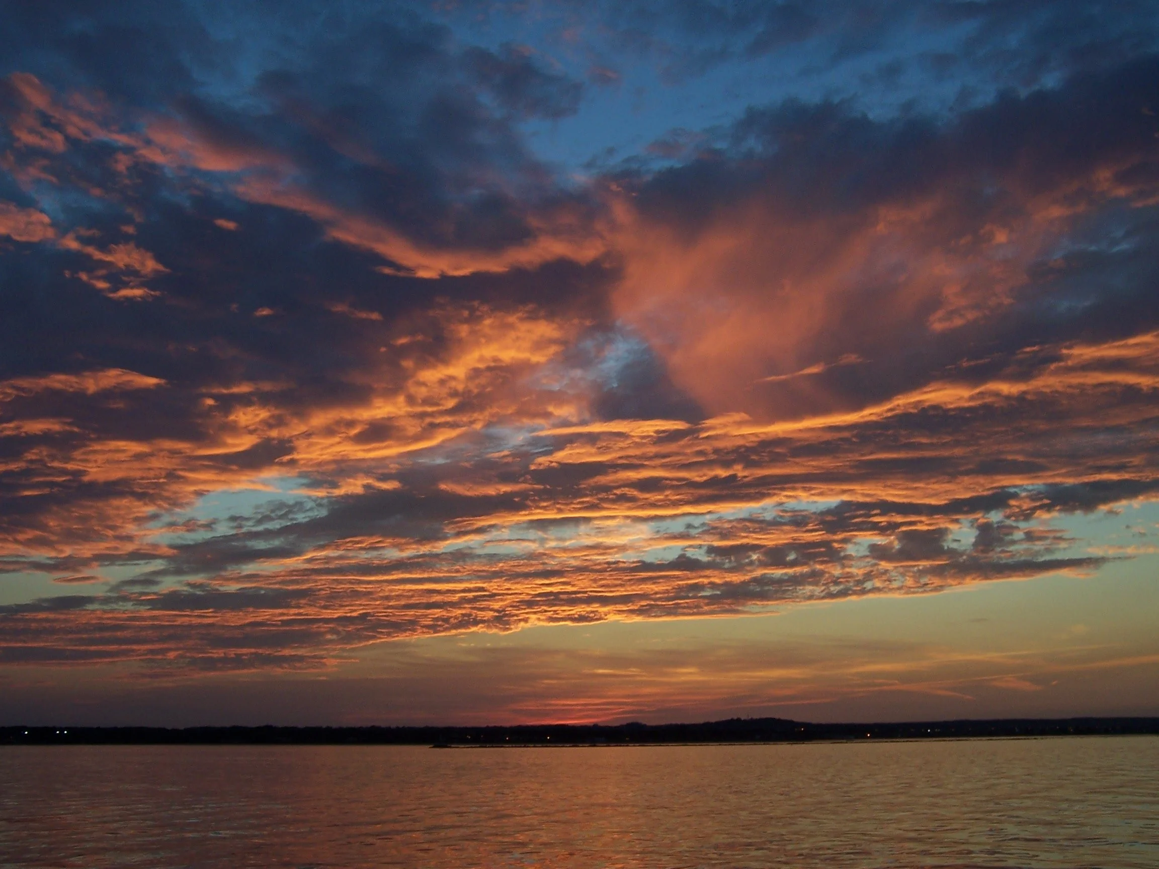 Sunset over a large body of water with colorful clouds in the sky