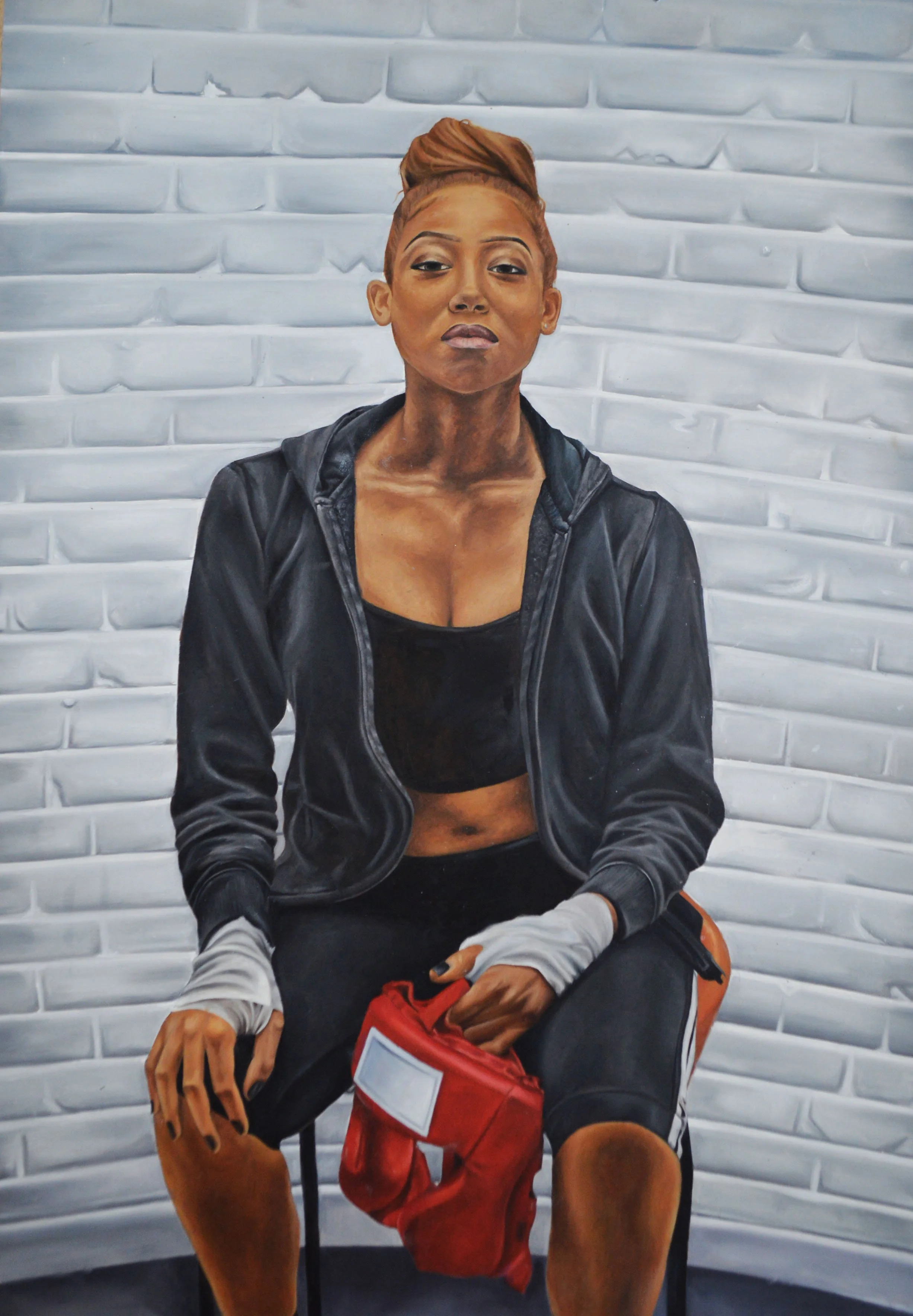 A realistic mural of a young woman with a confident pose, sitting against a textured white brick wall. She has a serious expression, wears athletic clothing including a black sports bra, a black zip-up jacket, and shorts, with her hair styled in an u