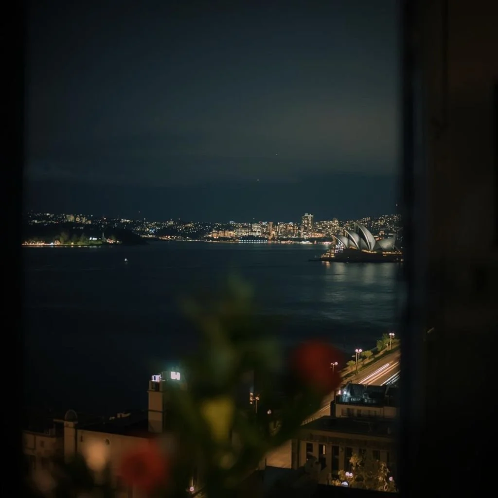 A quiet late-night view of Sydney city lights from an apartment, capturing the calm energy of the city after dark.