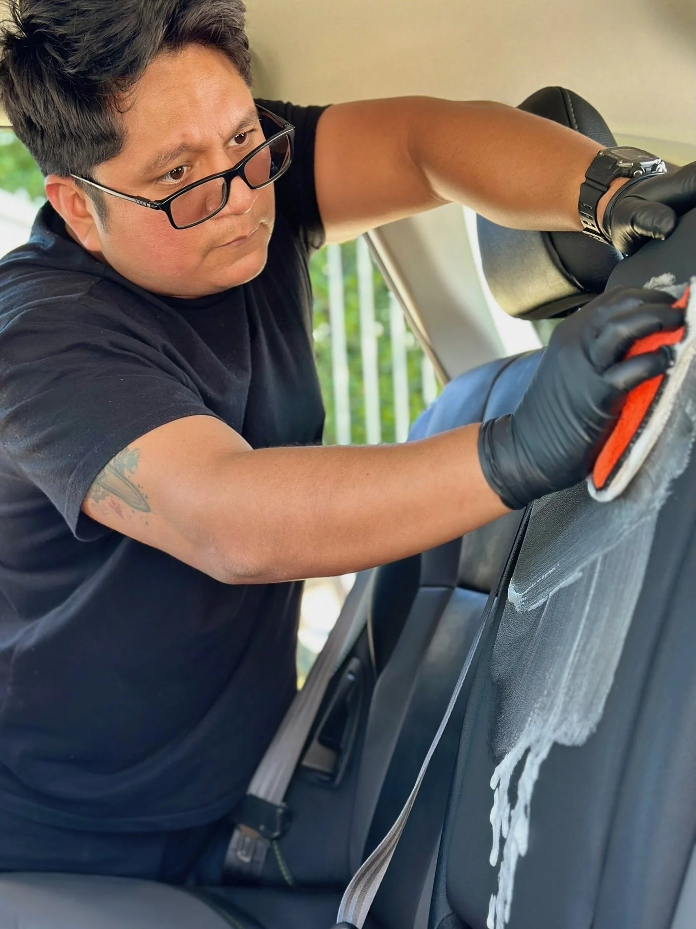 Owner of Alchemy Mobile Detailing carefully cleaning a vehicle's leather interior during a mobile detailing appointment in the San Fernando Valley.