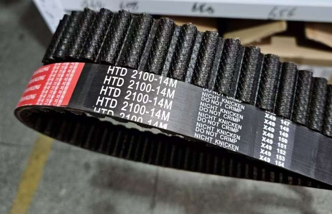 A coil of black timing belt with a red and black label that reads "HTD 2100-14M" and contains additional product information.