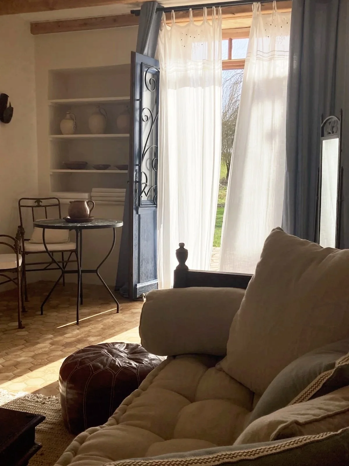 Sitzbereich für Gäste im kleinen Salon mit Blick auf den Garten, helle Möbel und Fensterlicht