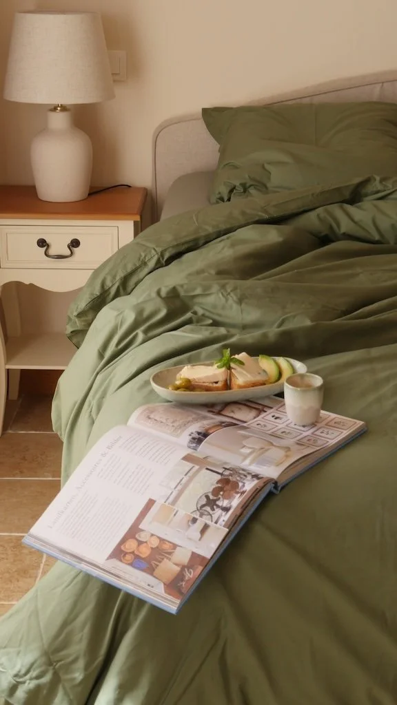 Schlafzimmerausschnitt mit Doppelbett, grüner Bettwäsche und Nachttisch mit Lampe in einem Chambres d’hôtes in Saint-Maigrin in der Charente-Maritime