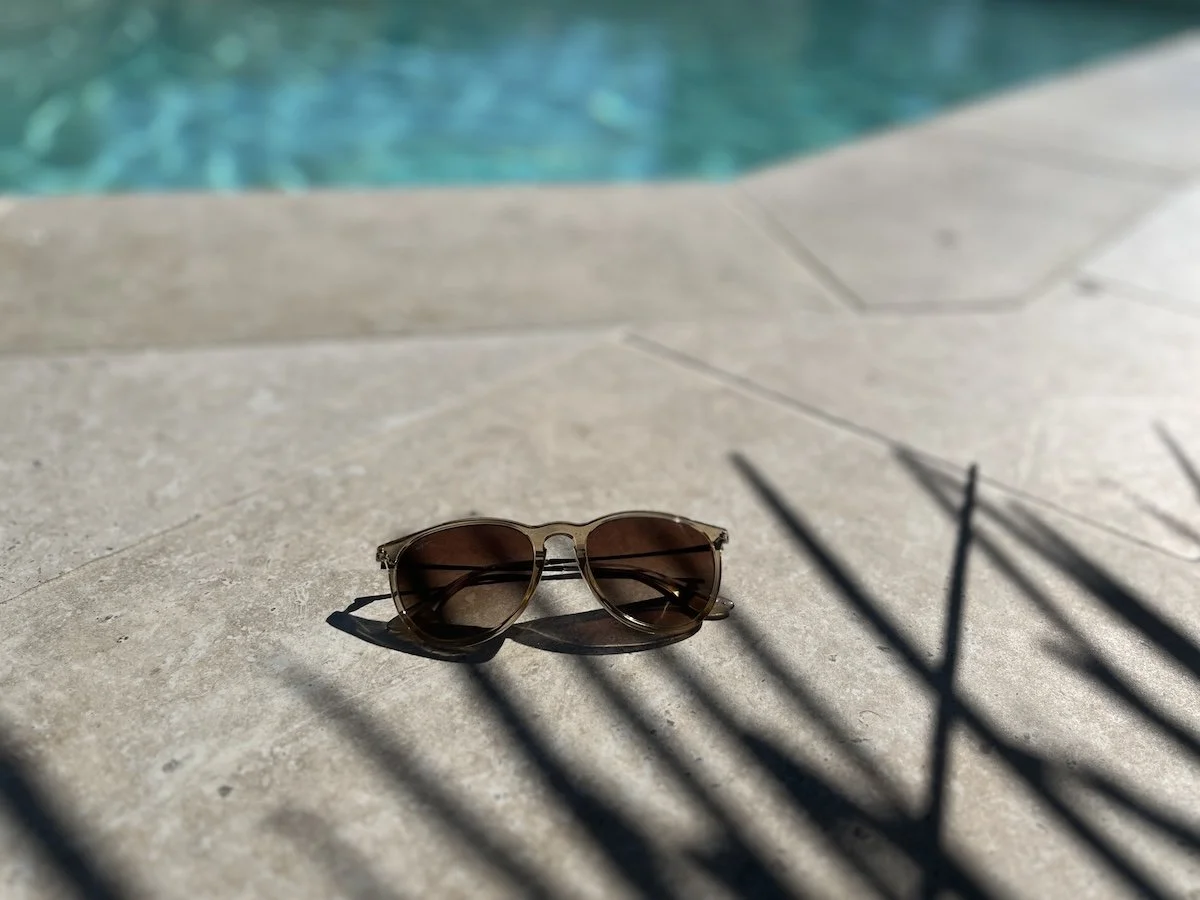 Ausschnitt der Poolterrasse mit Sonnenbrille und Schatten