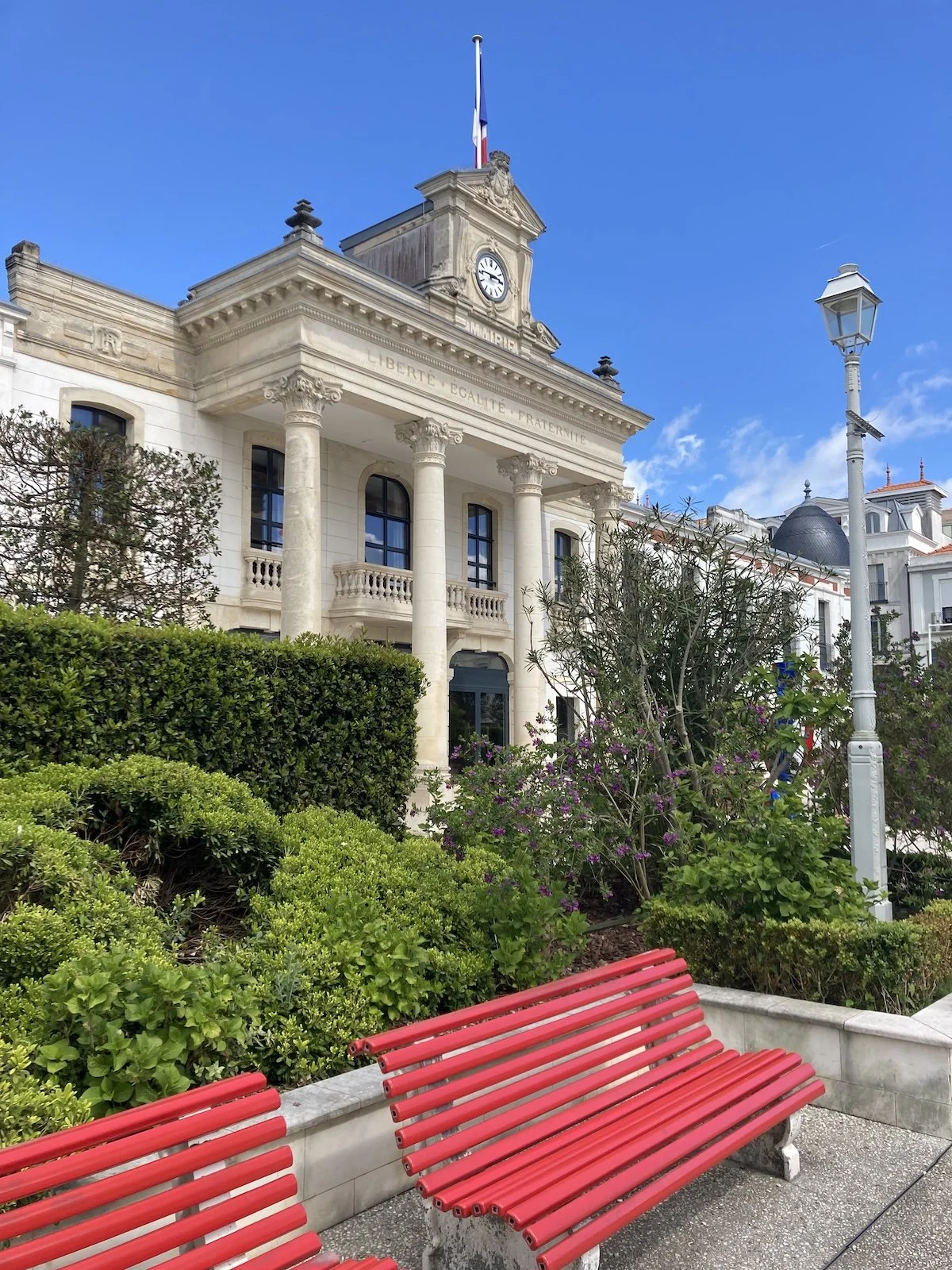 Seitlicher Blick auf das Rathaus von Arcachon, Frankreich, mit roter Sitzbank im Vordergrund