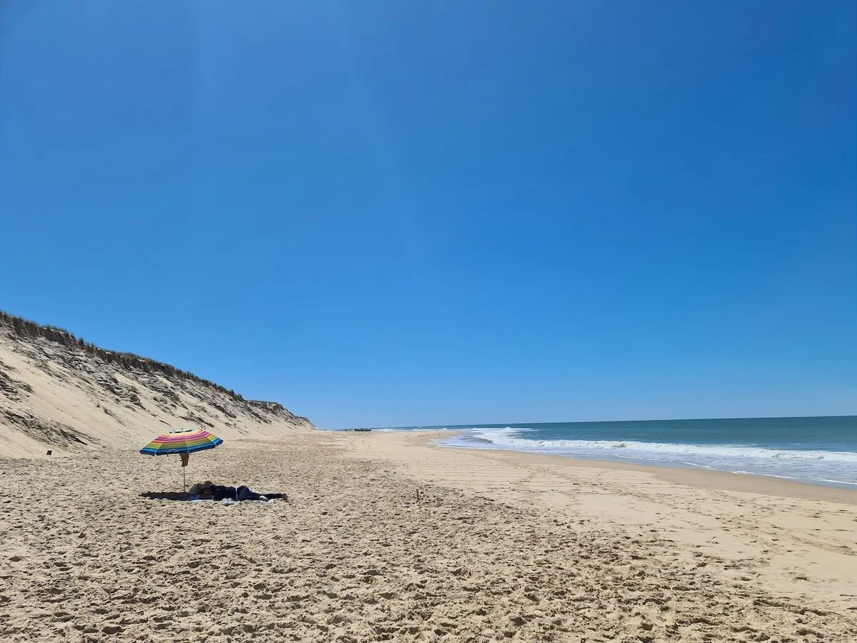 Menschenleerer Strandabschnitt an der Côte Sauvage, Atlantikküste Frankreichs, mit buntem Sonnenschirm