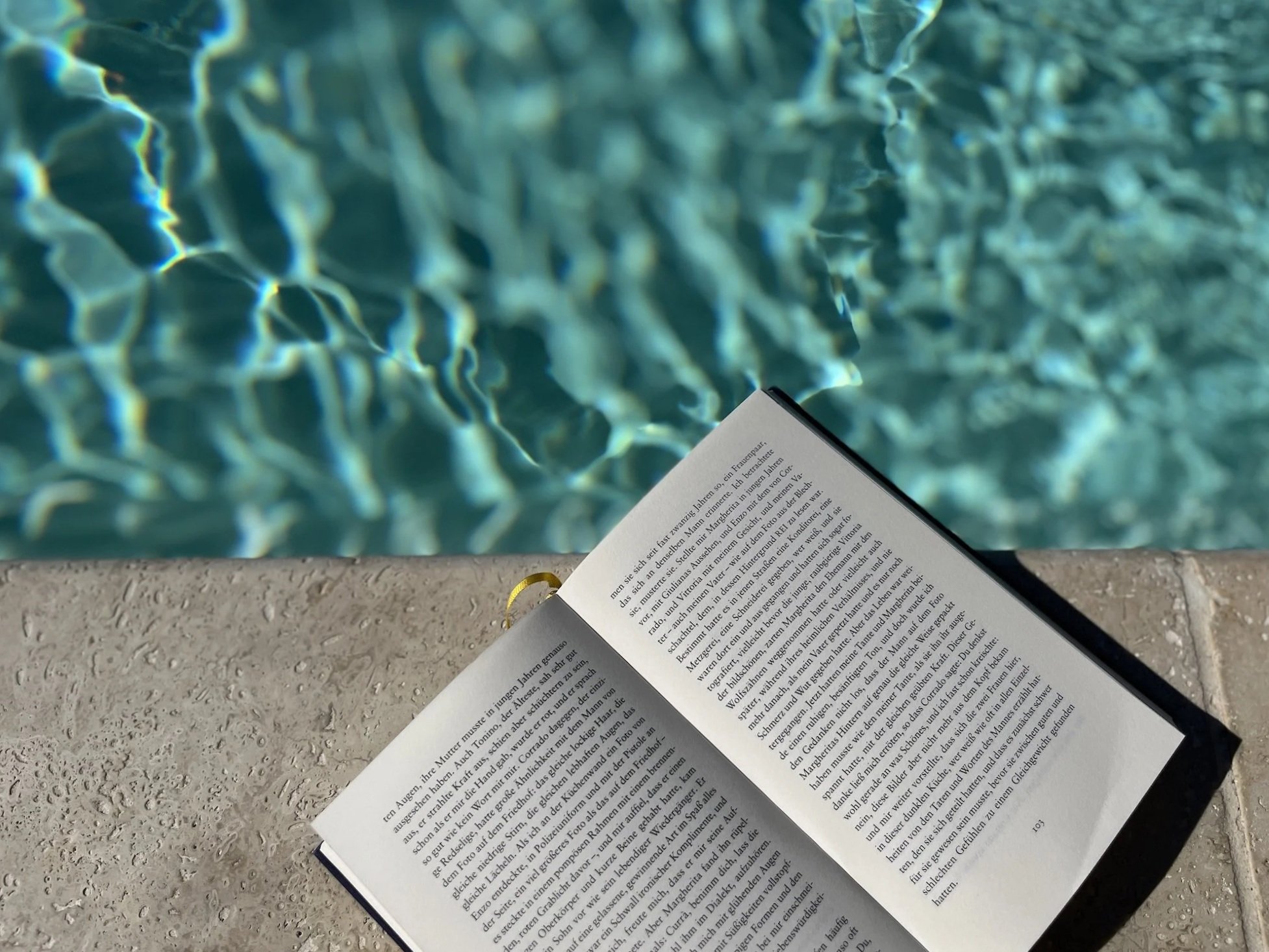 Pool und Terrasse einer Chambre d’hôtes mit geöffnetem Buch in entspannter Atmosphäre