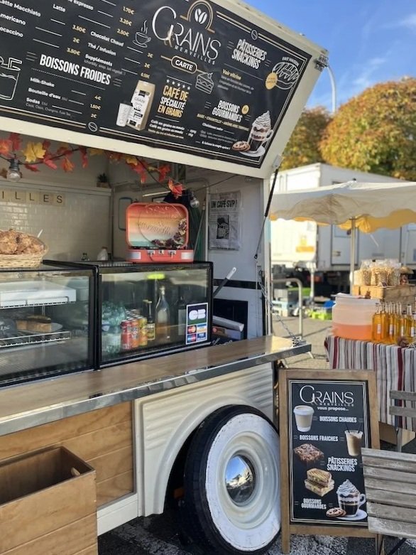 Mobiles Wandercafé auf dem Wochenmarkt in Barbezieux, Frankreich, mit Gästen und bunten Marktständen