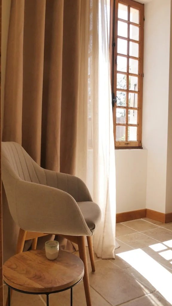 Helles Gästezimmer mit Sitzecke und geöffnetem Fenster in einer Chambre d’hôtes