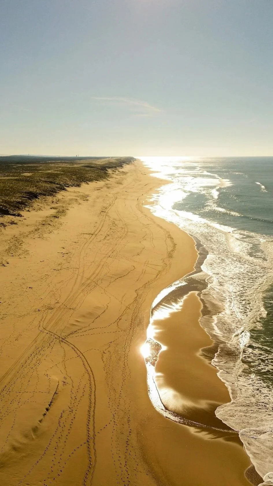 Langer, leuchtender Sandstrand am Cap Ferret, Atlantikküste Frankreichs, mit blauem Himmel und Wasser