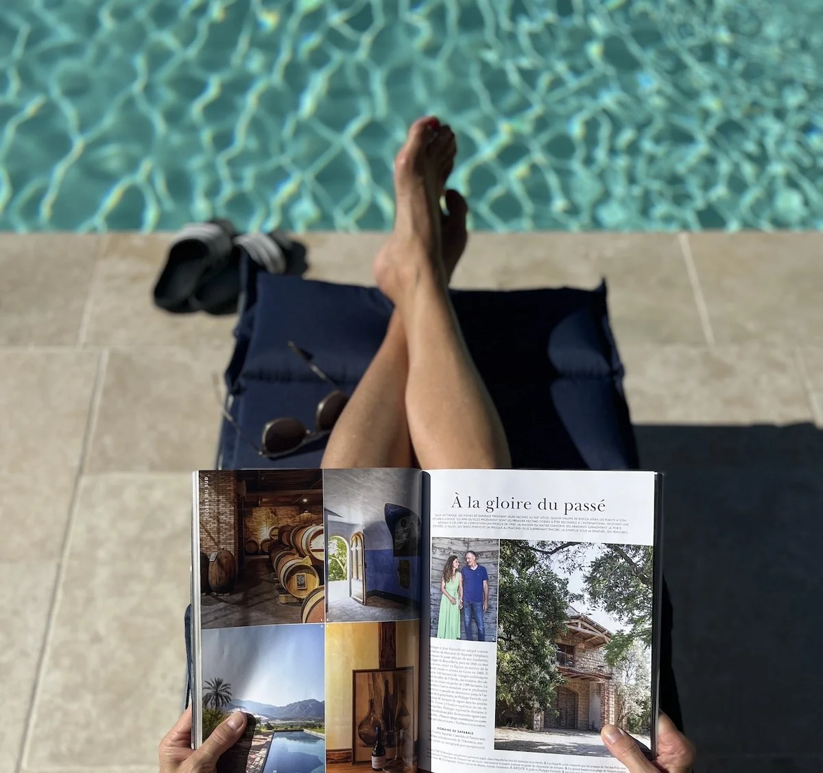 Ausschnitt einer Frau am Pool auf blauer Liege mit französischem Magazin