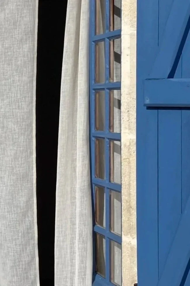 Blaues geöffnetes Fenster mit Vorhang in einem Gästezimmer einer Chambre d’hôtes in der Charente-Maritime