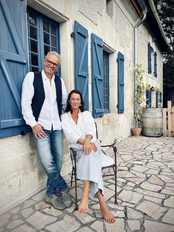 Frontansicht eines Landhauses mit Gastgeber auf der Terrasse und Hunden in gemütlicher Atmosphäre