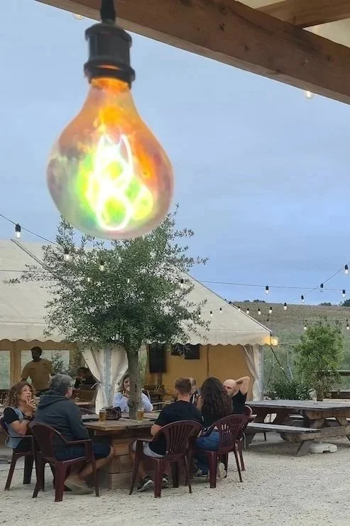 Pop-up-Restaurant in Frankreich bei Abendlicht, Tische mit Gästen und Beleuchtung