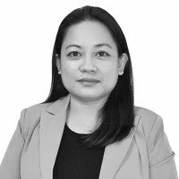 Black and white portrait of a woman with shoulder-length hair, wearing a blazer and a top, looking at the camera