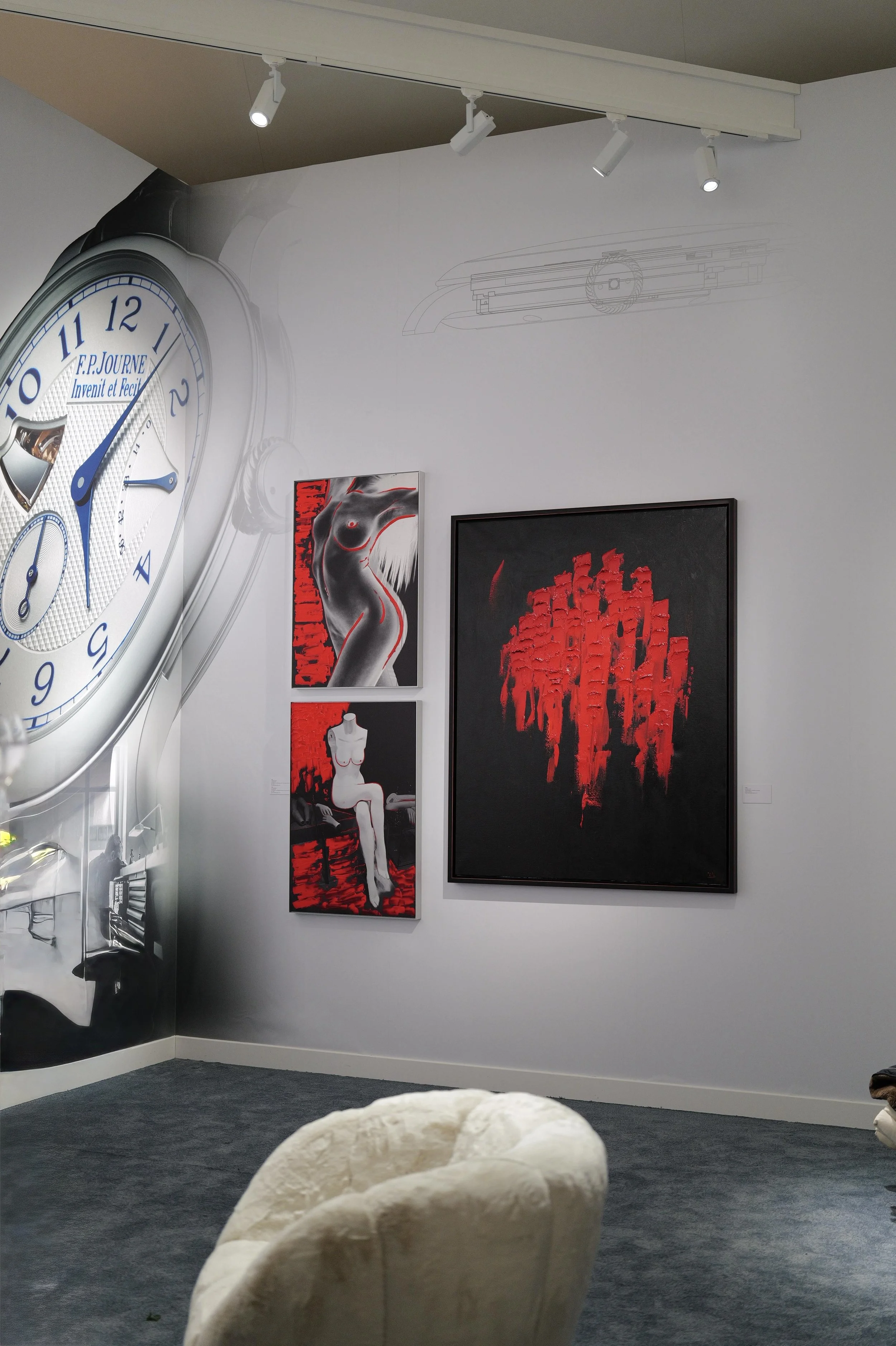 Une salle d'exposition avec un grand mur décoré d'une horloge mural, d'œuvres d'art modernes, et une banquette en coton beige.