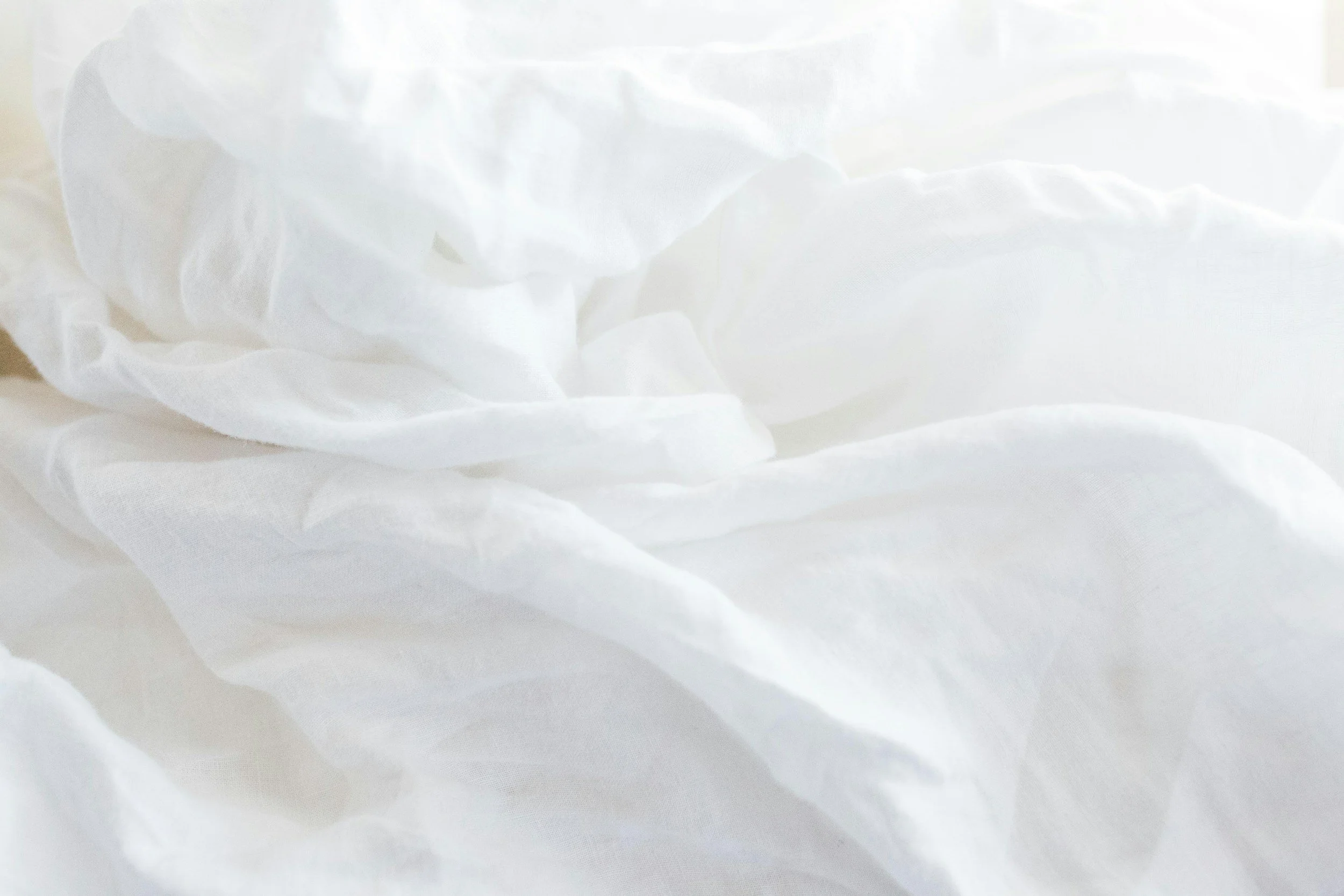 Close-up of white cotton fabric with soft shadows.