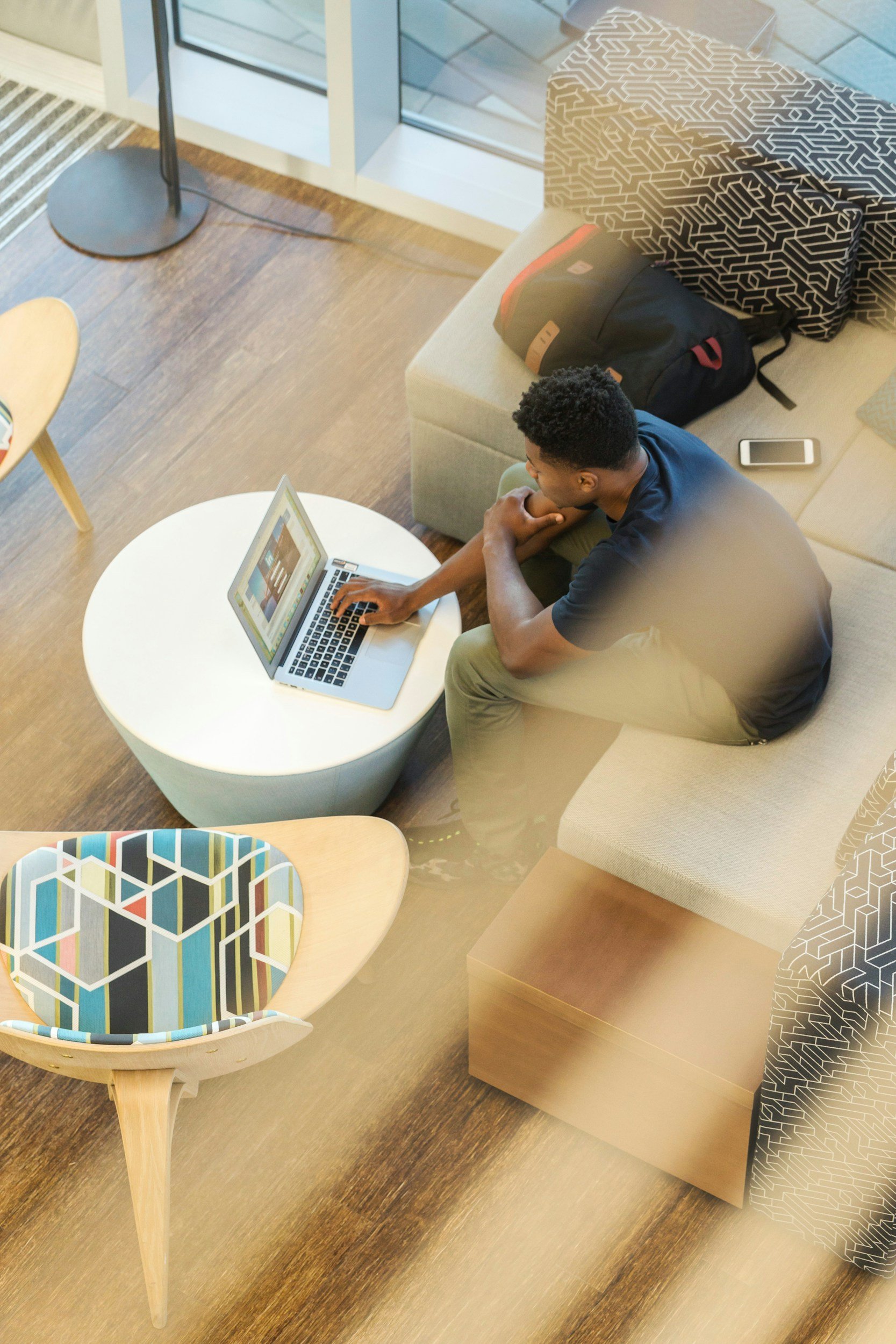 A man sitting in a waiting room of an office looking for a job on his laptop.