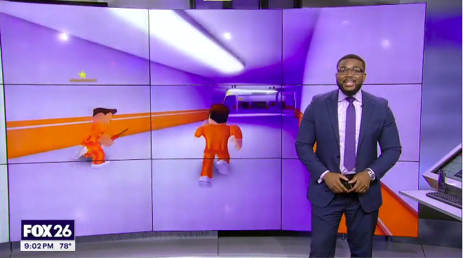 News anchor standing in front of a large screen displaying animated characters running through a brightly lit tunnel.