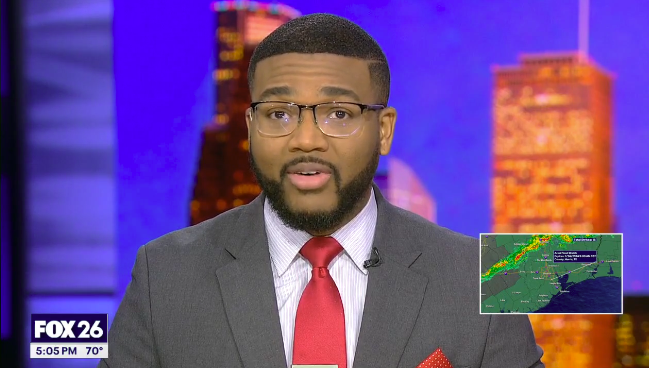 Television news anchor on FOX 26 presenting weather news, with a cityscape background and a weather map inset.