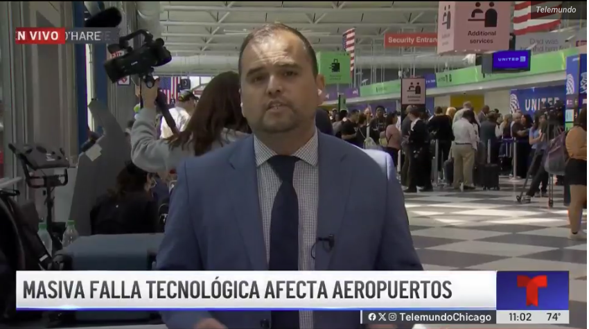TV news reporter covering a story at an airport with passengers in the background, discussing a massive technological failure affecting airports.