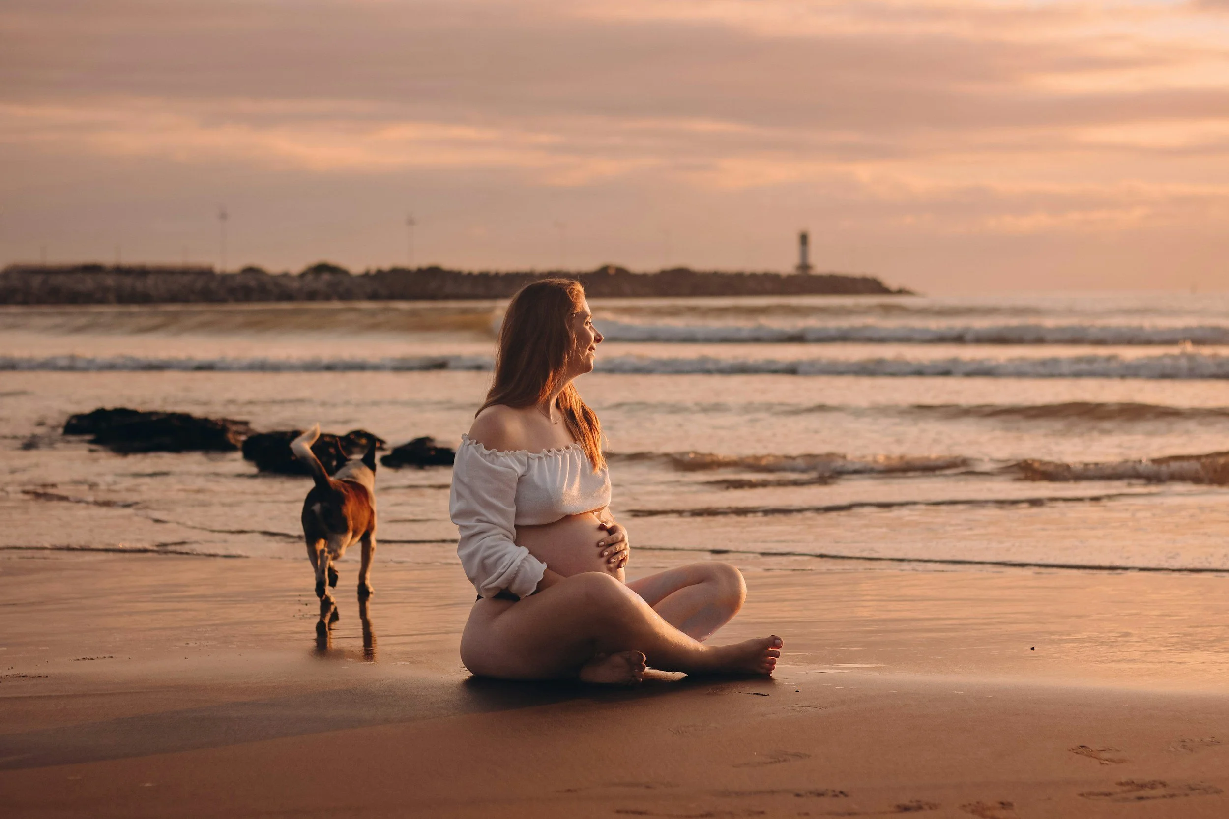 Pregnant woman on beach with dog