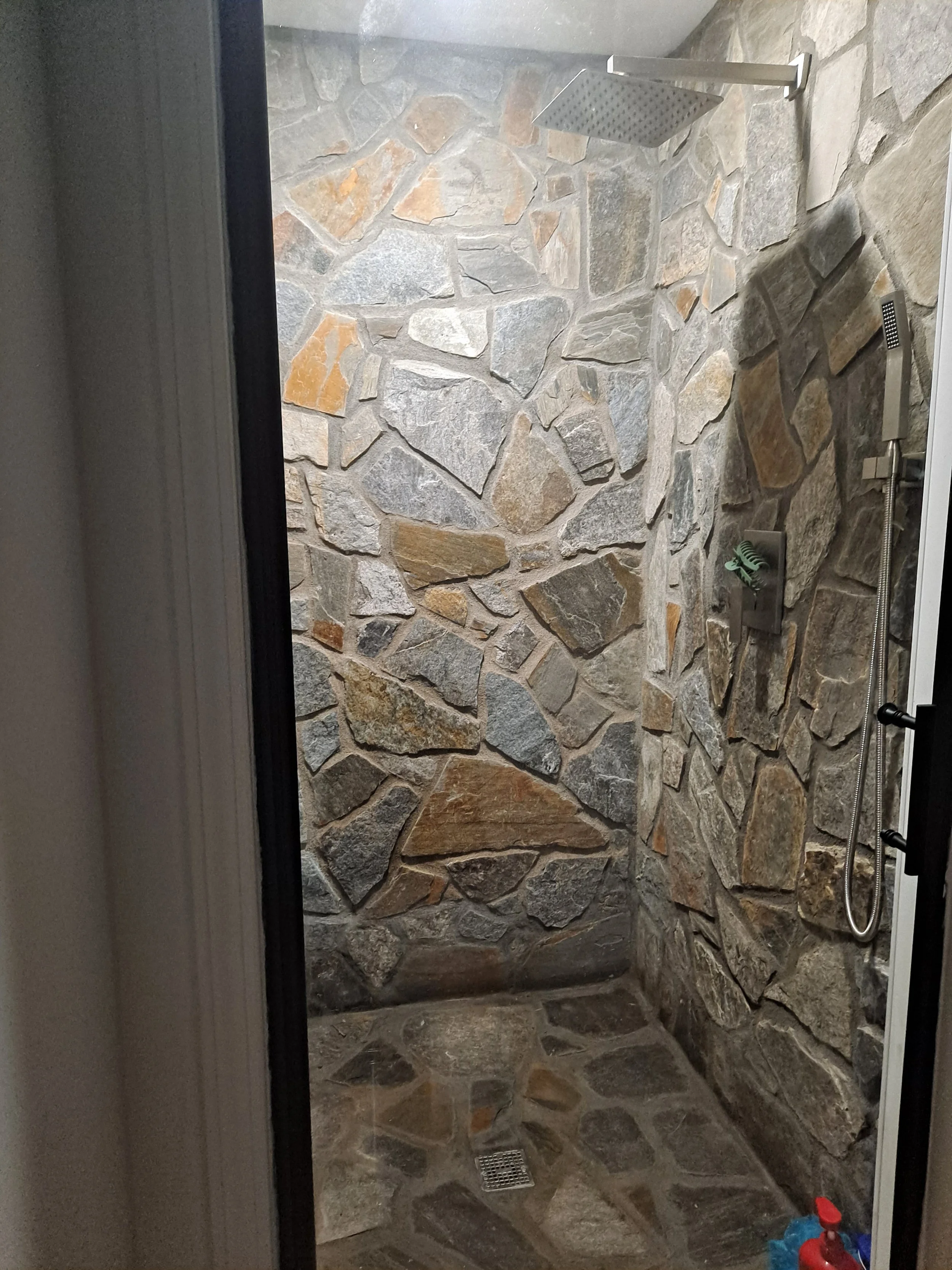 Stone-surround shower with a rain showerhead and a handheld showerhead.