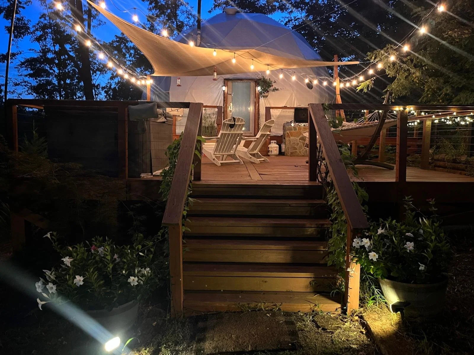 Treetops Dome and private deck at Carolina Domes in Union Mills, North Carolina, glowing under string lights at dusk.