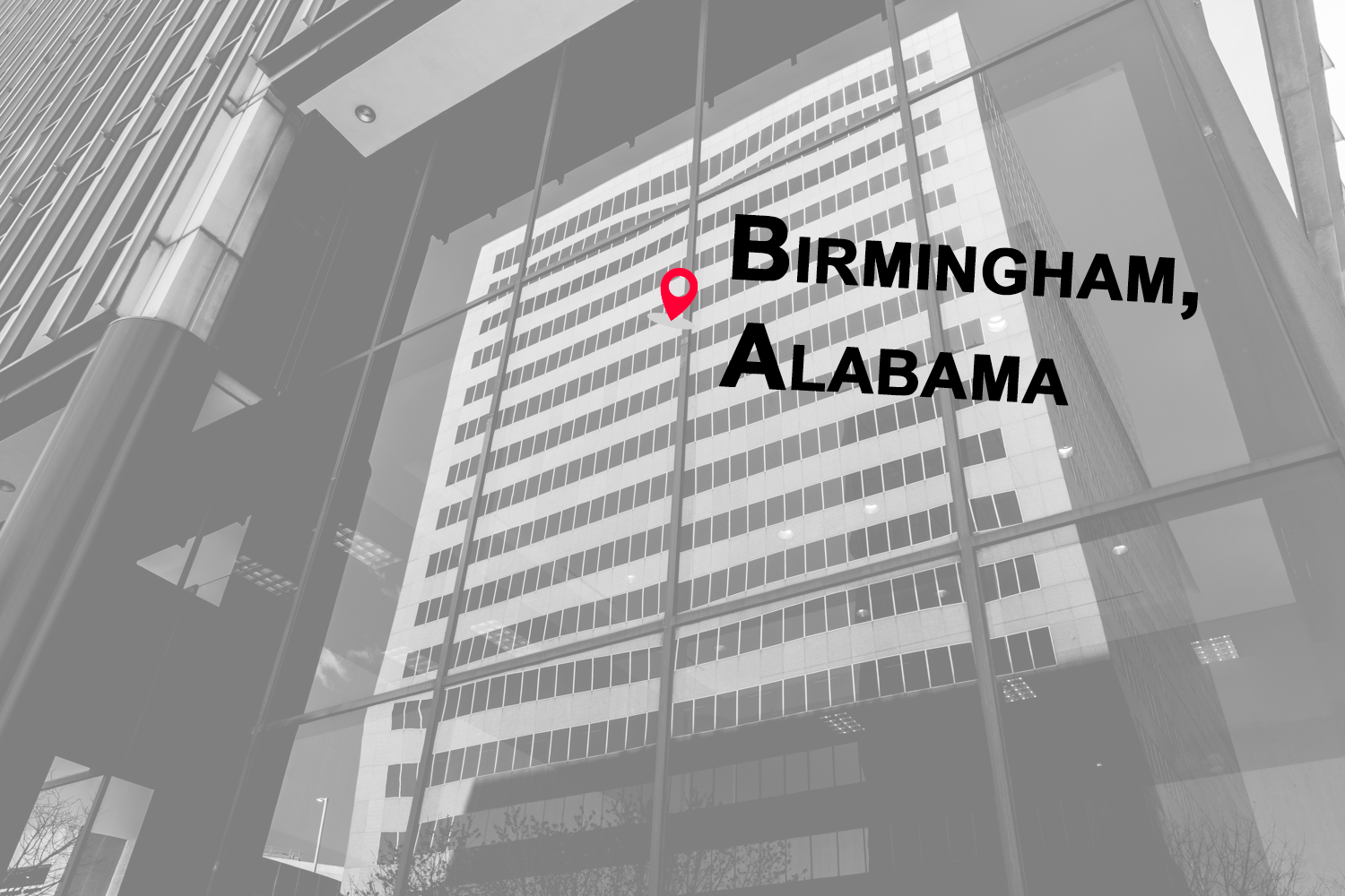 Reflection of a tall office building in glass window with the words "BIRMINGHAM, ALABAMA" written on the window and a location pin icon above.