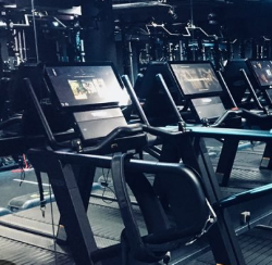 Row of modern treadmill exercise machines in a gym, illuminated with blue lighting.